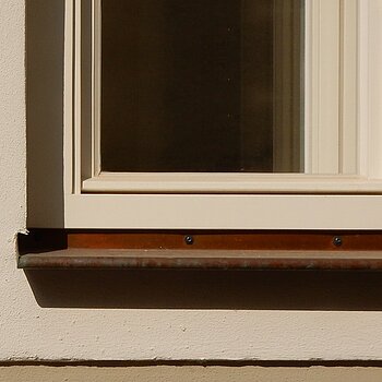 Detailausschnitt mit Fasche und einem Fenster mit konstruktivem Wetterschutzschenkel