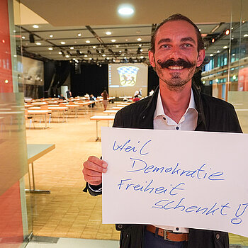 Sportreferent Jürgen Mieskes hält ein Schild mit der Aufschrift: "weil Demokratie Freiheit schenkt."