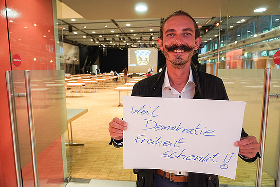 Sportreferent Jürgen Mieskes hält ein Schild mit der Aufschrift: "weil Demokratie Freiheit schenkt."