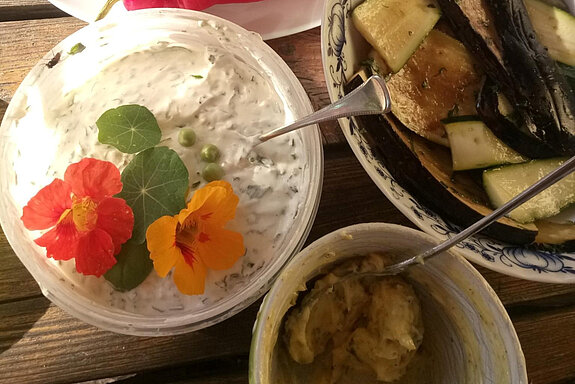 eine mit Blüten geschmückte Schüssel Frischkäse, gegrillte Zucchini