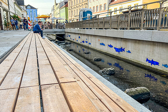 Das Fischmosaik schmückt nicht nur die nördliche Ufermauer, die Glassteine reflektieren auch im Wasser und vermitteln den Eindruck, dass die Fische durchs Wasser gleiten. (Foto: Stadt Freising)