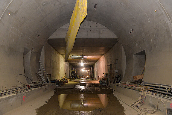 Durchgehend offen: Das Bild zeigt den Übergang von der bergmännischen Bauweise des Tunnels (mit dem Eiprofil) und der Deckelbauweise im Hintergrund. Der noch nicht abgenommene Belüftungsschlauch ist nicht mehr in Betrieb, da die natürliche Durchlüftung des Tunnels bereits funktioniert. (Foto: Stadt Freising)