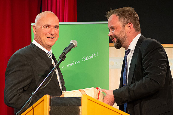 OB Tobias Eschenbacher bedankt sich bei Wolfgang Krebs, der schon bei der Gründungsveranstaltung aufgetreten war, für die unterhaltsame Darbietung. (Foto: Stadt Freising)