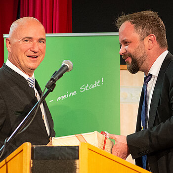 OB Tobias Eschenbacher bedankt sich bei Wolfgang Krebs, der schon bei der Gründungsveranstaltung aufgetreten war, für die unterhaltsame Darbietung. (Foto: Stadt Freising)