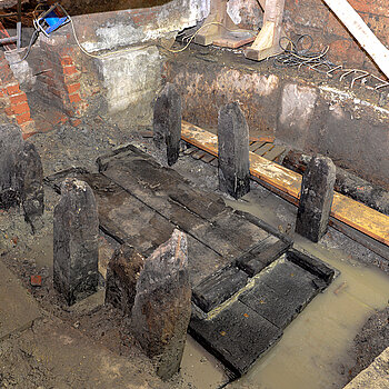 Die noch im Boden befindliche Holzkonstruktion muss jetzt ausgebaut werden, um die Einbauarbeiten der Drainagen unter dem Asamgebäude fortsetzen zu können. (Foto: Stadt Freising) 