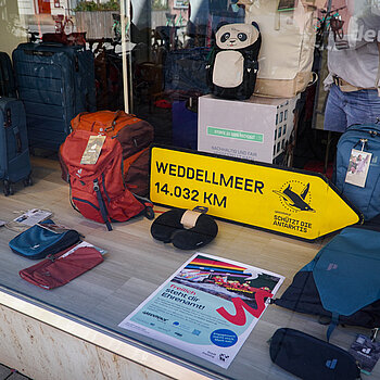 Taschen und Koffer, darunter ein gelber Wegweiser zum Weddelmeer und ein Plakat das für Engagement wirbt.