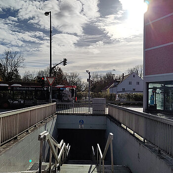 Blick über eine Treppe hinweg in eine Fußgängerunterführung, Rechts davon ein rosa gestrichenes Haus.