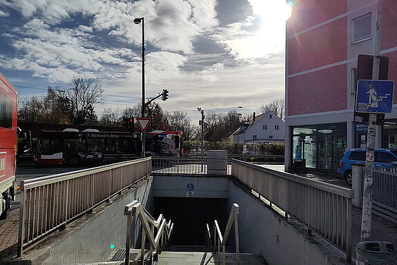 Blick über eine Treppe hinweg in eine Fußgängerunterführung, Rechts davon ein rosa gestrichenes Haus.