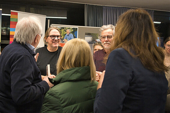 Energiesparkommissar Carsten Herbert signiert am Infostand der Agenda21 Energie und Klima sein Buch, Sepp Beck berät zu Wärmepumpen. Foto: Bertram Hock 2 Männer an einem Stand sind von mehreren Menschen umringt.