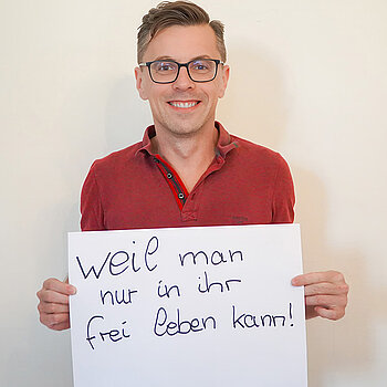 Stadtratsmitglied Dr. Jens Barschdorf. Foto: Stadt Freising Ein Mann in einem roten Hemd zeigt ein Schild mit der Aufschrift: "weil man nur in ihr frei leben kann!"